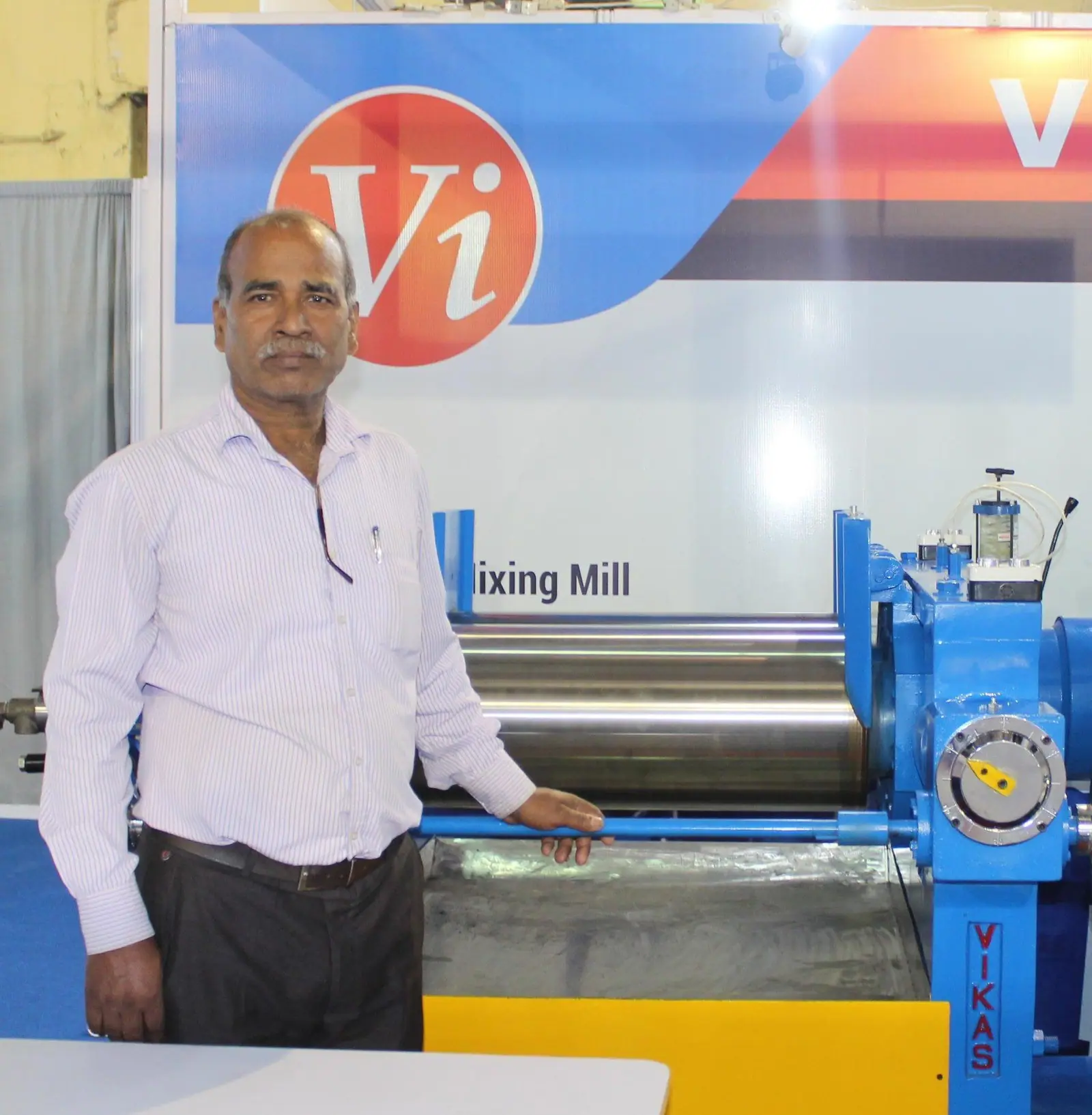 Santram Yadav, founder, beside a VIKAS mixing mill at a trade expo